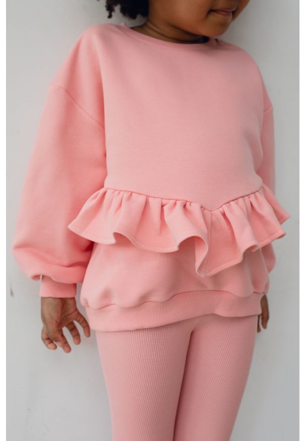 Marsala - MINI bluza oversize z falbanką na dole w kolorze PASTEL PINK - ANGEL-104-110 (4-5). Kolor: różowy. Materiał: materiał, dzianina, poliester, bawełna, guma. Długość rękawa: długi rękaw. Długość: długie. Wzór: gładki, haft