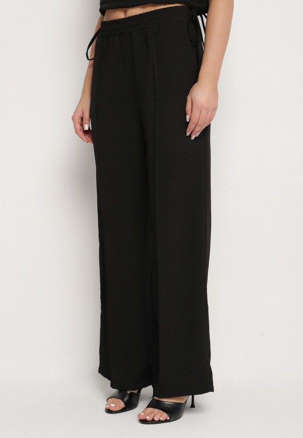 Born2be - Czarny Komplet Kopertowa Bluzka z Kwiatową Broszką i Szerokie Spodnie Reavilia. Kolor: czarny. Wzór: kwiaty