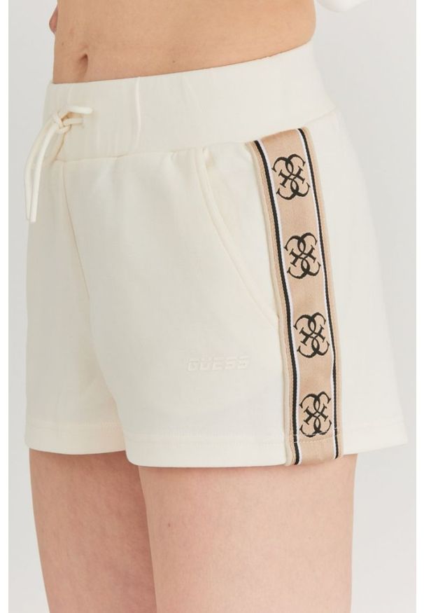 Guess - GUESS Kremowe szorty damskie z lampasami w logo. Kolor: biały. Materiał: bawełna. Wzór: aplikacja
