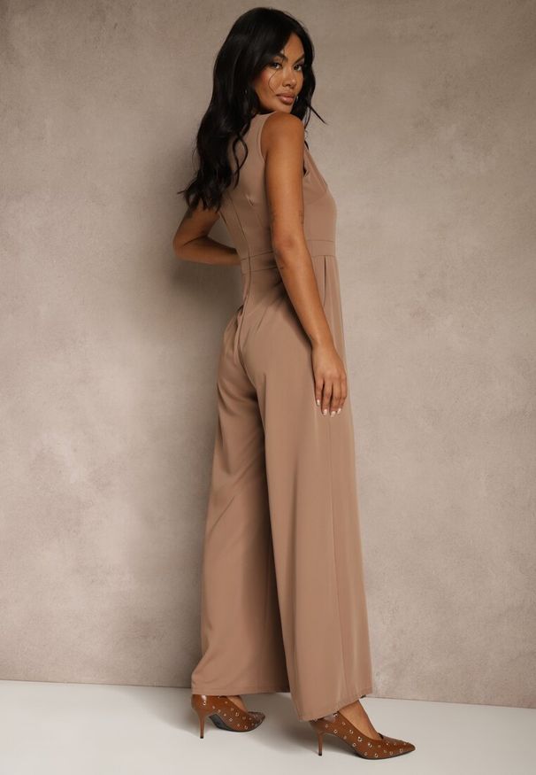 Renee - Ciemnobeżowy Taliowany Kombinezon Ozdobiony Zakładkami Berinola. Okazja: na imprezę. Kolor: beżowy. Wzór: aplikacja. Styl: wizytowy, elegancki