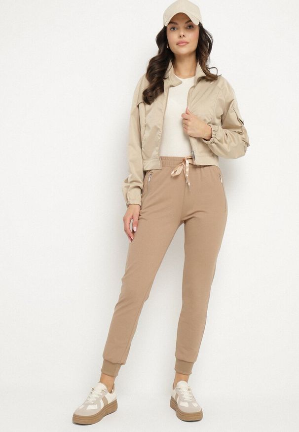 Born2be - Ciemnobeżowe Bawełniane Spodnie Dresowe ze Ściągaczami i Wysokim Stanem Glindda. Okazja: na co dzień. Stan: podwyższony. Kolor: beżowy. Materiał: bawełna, dresówka. Styl: klasyczny, casual, elegancki