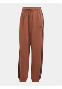 Adidas - adidas Spodnie dresowe Essentials 3-Stripes IL3451 Brązowy Loose Fit. Kolor: brązowy. Materiał: bawełna