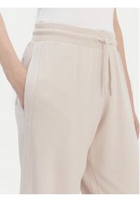 TOMMY HILFIGER - Tommy Hilfiger Spodnie dresowe UW0UW04771 Beżowy Relaxed Fit. Kolor: beżowy. Materiał: dresówka #5