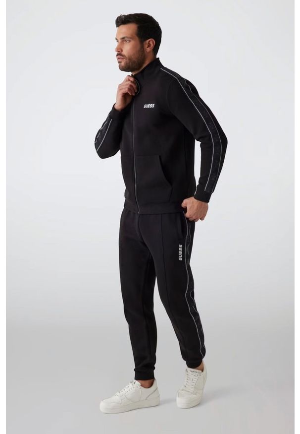 Guess - GUESS Czarne męskie spodnie dresowe z lampasami Mickey, Rozmiar L. Kolor: czarny. Materiał: dresówka