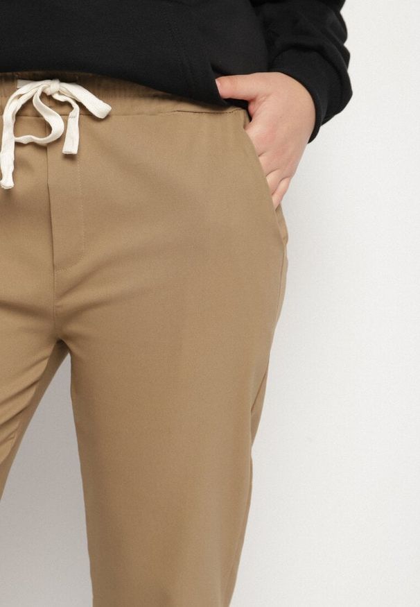 Born2be - Ciemnobeżowe Spodnie z Bawełny z Powiniętymi Nogawkami i Sznurkiem Savarile. Okazja: na co dzień. Kolor: beżowy. Materiał: bawełna. Styl: casual