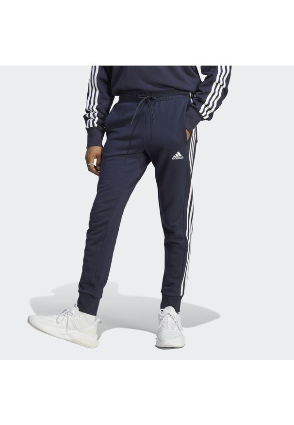 Adidas - Spodnie dresowe męskie adidas Essentials French Terry Tapered Cuff 3-Stripes. Kolor: biały, wielokolorowy, czarny, niebieski. Materiał: dresówka