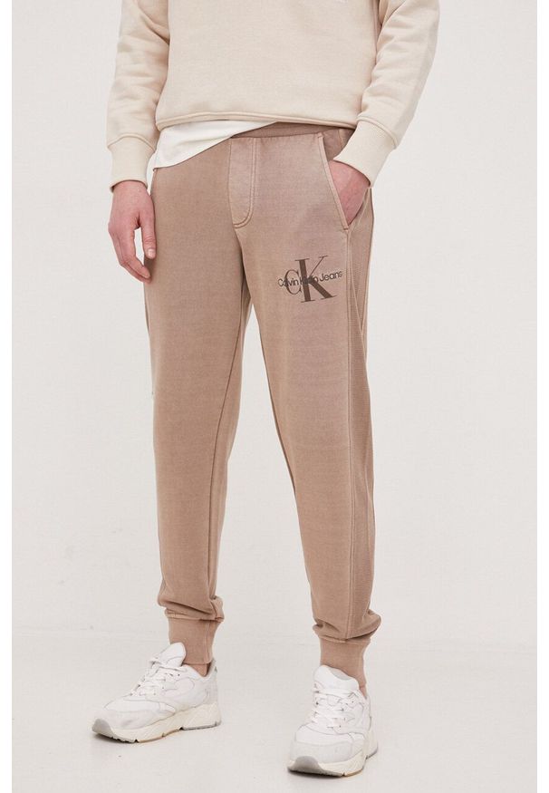 Calvin Klein Jeans spodnie dresowe bawełniane kolor brązowy gładkie. Kolor: brązowy. Materiał: bawełna, dresówka. Wzór: gładki