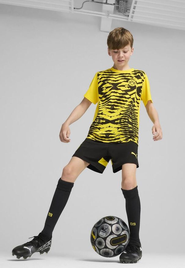 Puma - Młodzieżowa koszulka przedmeczowa z krótkim rękawem Borussia Dortmund PUMA. Kolor: czarny, wielokolorowy, żółty. Długość rękawa: krótki rękaw. Długość: krótkie