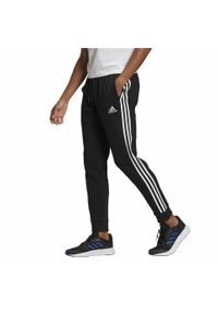 Adidas - Essentials Fleece Tapered Cuff 3-Stripes Pants. Kolor: biały, czarny, wielokolorowy. Materiał: polar. Sport: fitness