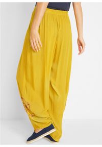 Spodnie z szerokimi nogawkami, wygodnym paskiem w talii i nadrukiem z boku bonprix żółty curry. Kolor: żółty. Wzór: nadruk #5