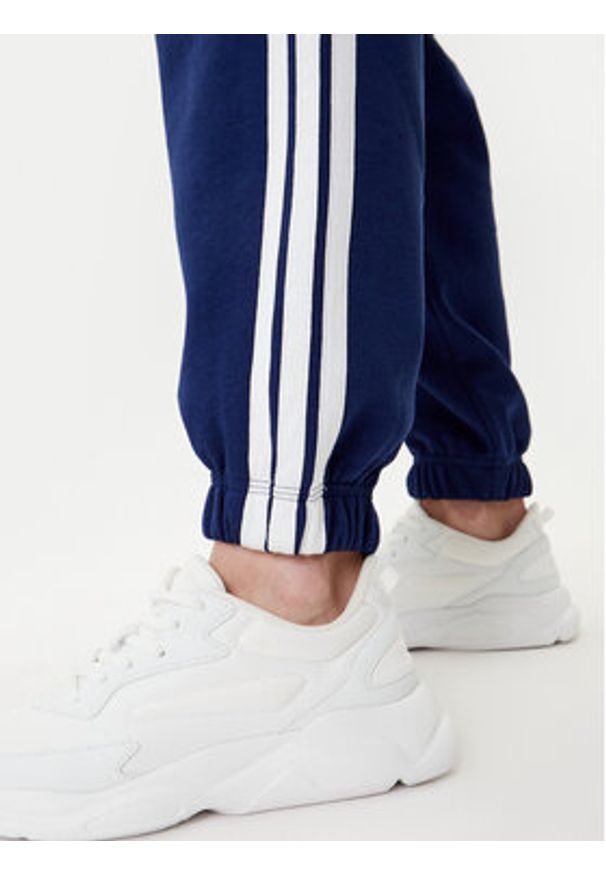Adidas - adidas Spodnie dresowe Essentials 3-Stripes Fleece JX7696 Niebieski Loose Fit. Kolor: niebieski. Materiał: syntetyk