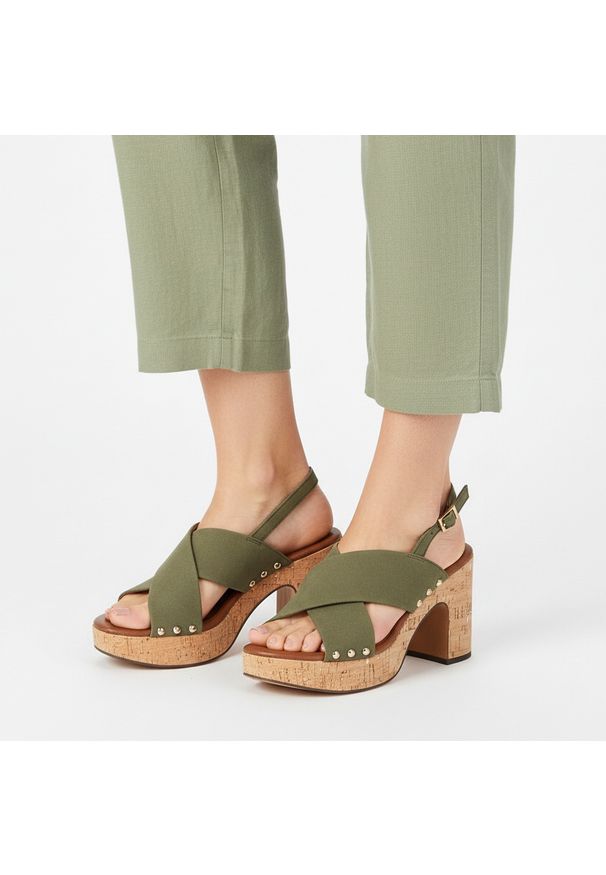 Sandały damskie Marco Tozzi, na wysokim słupku z krzyżowanymi paskami i regulowanym zapięciem przy pięcie osadzone na platformie o korkowym wykończen. Zapięcie: pasek. Kolor: zielony. Materiał: len. Wzór: paski. Sezon: lato. Obcas: na platformie. Styl: elegancki, klasyczny. Wysokość obcasa: średni