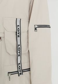 Born2be - Beżowy Płaszcz z Regulowaną Długością i Taśmami z Napisem Emmilou. Kolor: beżowy. Wzór: napisy. Sezon: wiosna, jesień #3