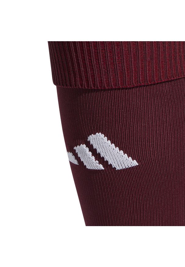 Getry piłkarskie Adidas Milano 23. Kolor: czerwony, wielokolorowy, brązowy. Sport: piłka nożna